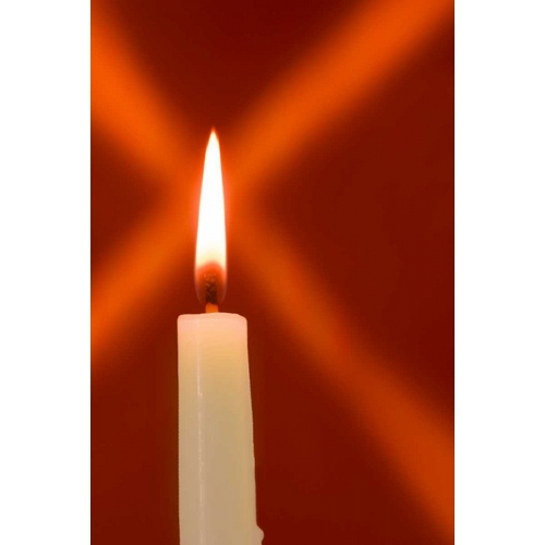 Burning candle with star burst on red background